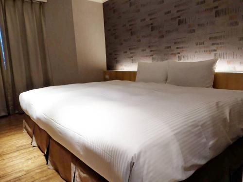 高雄的住宿－簡單生活商旅，一张配有白色床单和枕头的大床