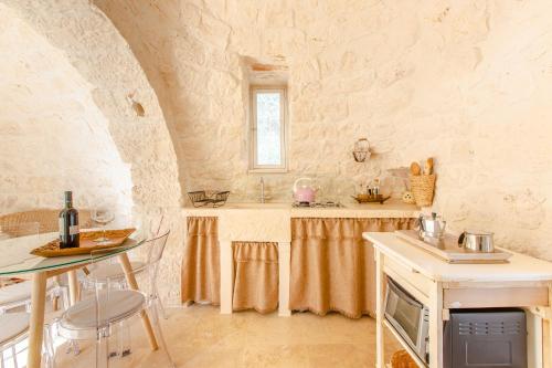 Una cocina con mesa y fregadero empotrados en una pared de piedra. en Il trullo della Quercia, en San Michele Salentino
