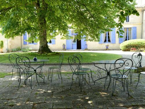 un groupe de tables et de chaises sous un arbre dans l'établissement Chambres d'Hôtes La Sauvageonne, à Saint-Palais