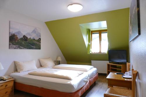 a small bedroom with a bed and a television at Altstadt-Hotel Zum Hechten in Füssen