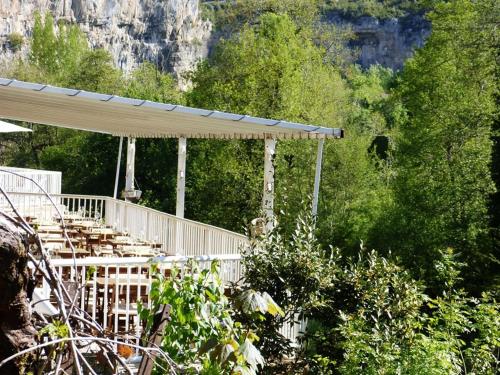 a patio with a roof with trees and mountains at Hôtel Restaurant des Grottes du Pech Merle in Cabrerets
