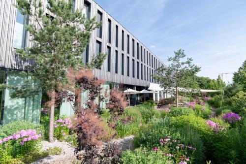 a garden in front of a building with flowers at Bader Hotel in Parsdorf