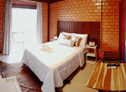 a bedroom with a large white bed and a brick wall at Pousada Doce Mar in Guarda do Embaú