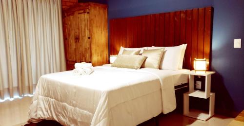a bedroom with a large white bed with two lamps at Pousada Doce Mar in Guarda do Embaú