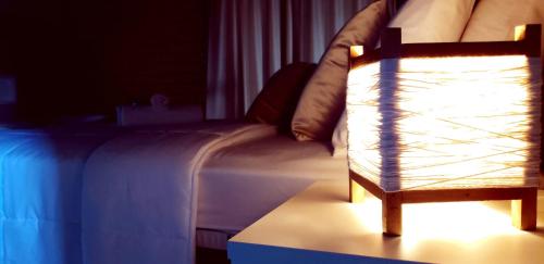 a bedroom with a bed with a lamp on a table at Pousada Doce Mar in Guarda do Embaú