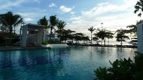 a large swimming pool with palm trees in the background at The Relaxing Room Sea View at Lumpini Park Beach Jomtien Condominium Pattaya in Jomtien Beach