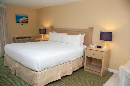 a bedroom with a large white bed and a phone at InnSeason Resorts Surfside in Falmouth