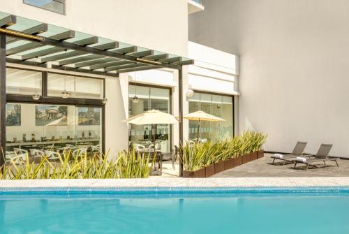 a swimming pool in front of a house at Fiesta Inn Guadalajara Aeropuerto in Guadalajara
