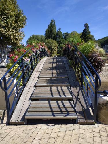 a wooden bridge with flowers and plants on it at Hôtel Grand Confort Le Moulin Rouge in Terrasson-Lavilledieu