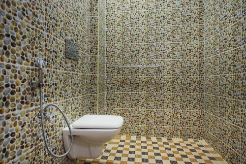 a bathroom with a toilet and a tiled wall at Hotel Rajeswari International in Kanyakumari