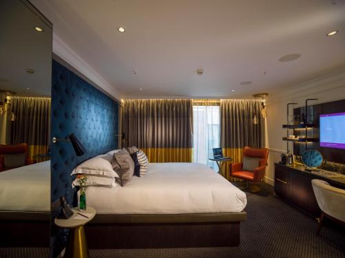 a hotel room with a bed and a flat screen tv at The Guardsman - Preferred Hotels and Resorts in London