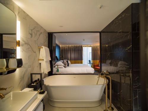 a bathroom with a bath tub and a bed at The Guardsman - Preferred Hotels and Resorts in London