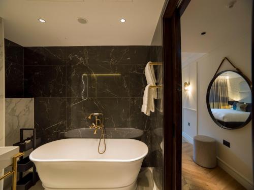 a bathroom with a tub and a mirror at The Guardsman - Preferred Hotels and Resorts in London