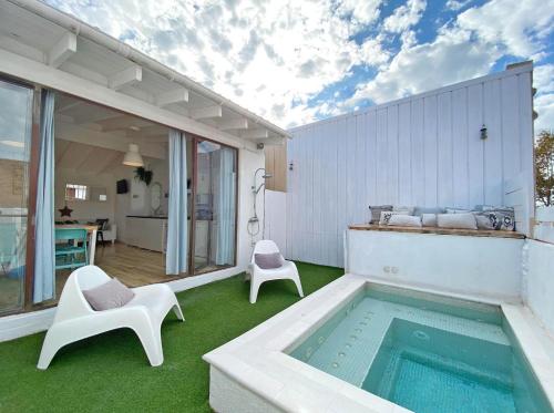 a patio with a swimming pool and two white chairs at Casa Aquamarine in Barcelona