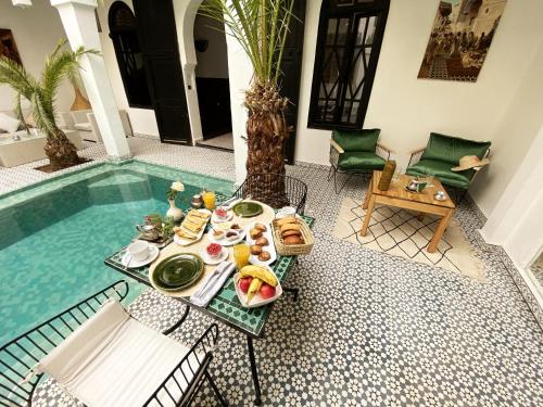 einen Tisch mit einem Teller Essen neben einem Pool in der Unterkunft Riad Fabiola Et Spa in Marrakesch