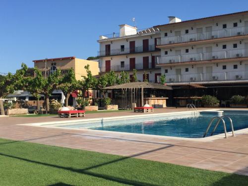 un hotel con piscina di fronte a un edificio di Hostal SolFina a Palafolls