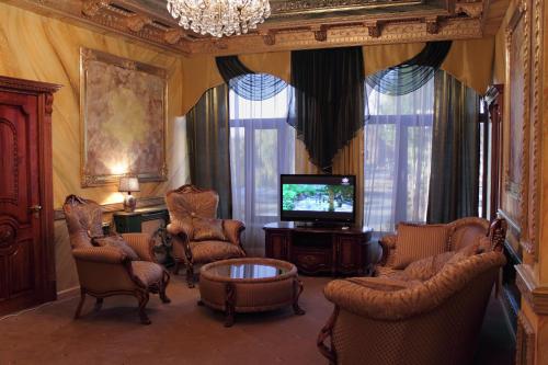 a living room with chairs and a tv and a table at Alexandrapol Palace Hotel in Gyumri