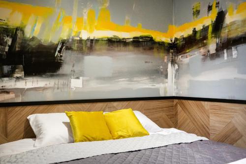 a bed with yellow pillows and a painting on the wall at iroom in Lublin