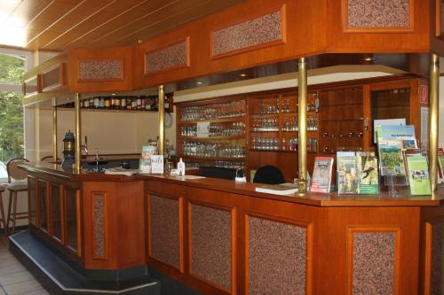 a bar in a restaurant with wooden cabinets at Hotel Bergische Schweiz in Velbert