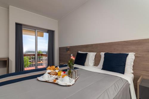 a large white bed with a tray of food on it at Hotel do Parque in Viana do Castelo