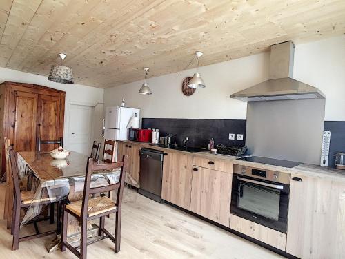 une cuisine avec une table et une cuisinière four supérieur dans l'établissement Maison de village spacieuse au calme, à Matemale