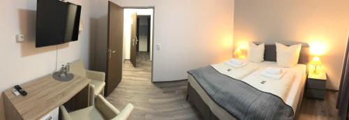 a hotel room with a bed and a desk and a television at Hotel Bad Driburg in Bad Driburg
