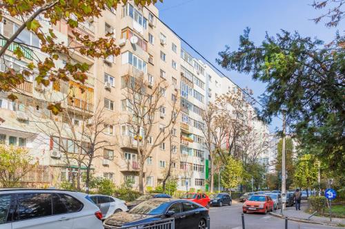 una calle con coches estacionados frente a un edificio alto en Timpuri Noi - Studio 54 by MRG Apartments, en Bucarest