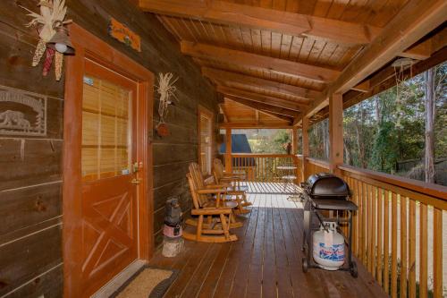 a porch of a cabin with a grill and chairs at Highland Dream, Hot Tub, FREE tickets each paid day, Near Dollywood, WIFI!!! in Sevierville
