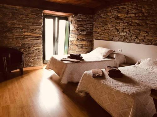 a bedroom with two beds and a stone wall at Pension Siete en el Camino in Sarria