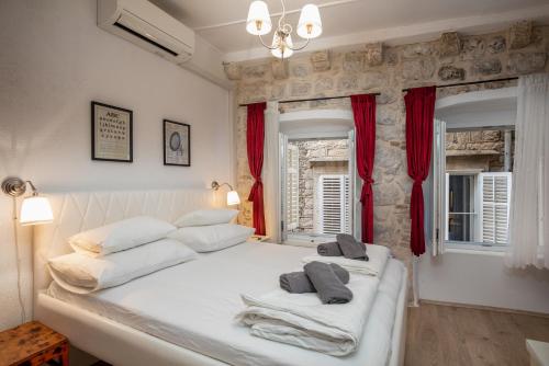 1 dormitorio con 1 cama blanca grande y cortinas rojas en Private Accomodation Linda, en Dubrovnik