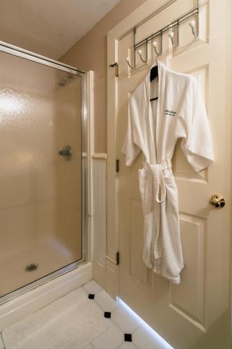 a bathroom with a shower and a robe hanging on a rack at The Inn at the Babcock House in Appomattox