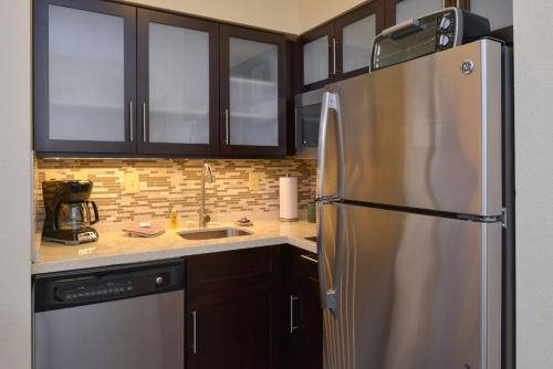La cuisine est équipée d'un réfrigérateur en acier inoxydable et de placards en bois. dans l'établissement Staybridge Suites Indianapolis-Fishers, an IHG Hotel, à Fishers