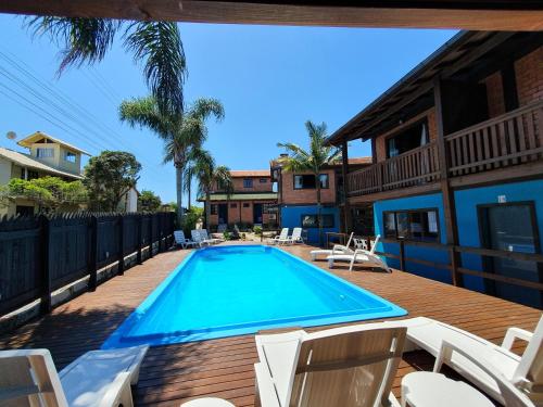 - une piscine sur une terrasse avec des chaises blanches dans l'établissement Pousada Doce Mar, à Guarda do Embaú