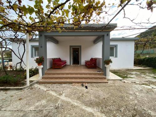 a white house with red chairs and a porch at Progon House in Tepelenë