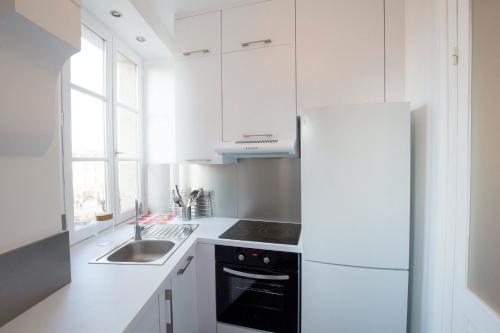 La cuisine blanche est équipée d'un évier et d'un réfrigérateur. dans l'établissement Place Saint Michel Apartment, à Bordeaux