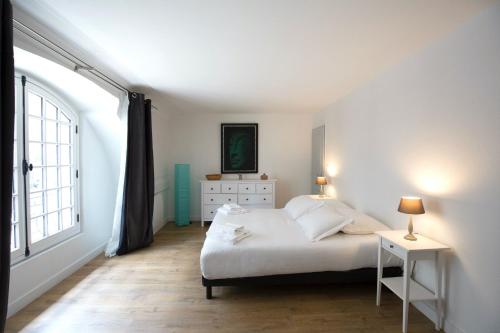 Un dormitorio blanco con una cama y una ventana. en Place du Palais, en Burdeos