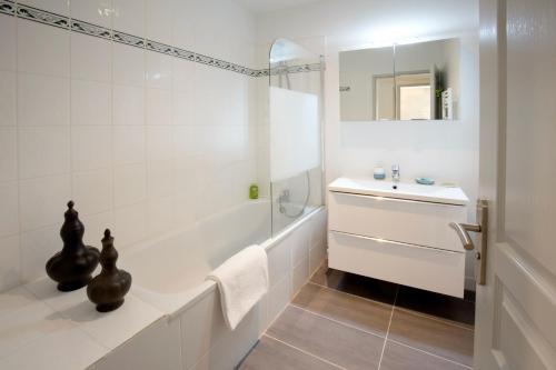 a white bathroom with a tub and a sink at Place du Palais in Bordeaux