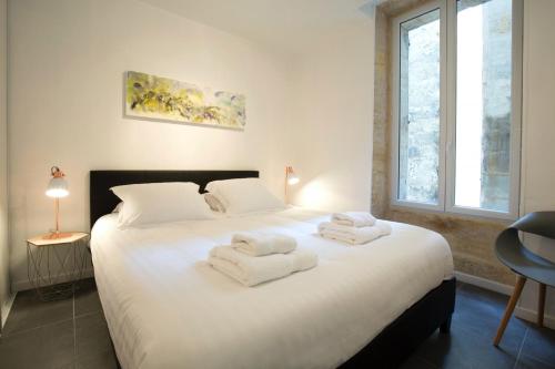 a bedroom with a large white bed with towels on it at Appartement Bordeaux Centre Historique in Bordeaux