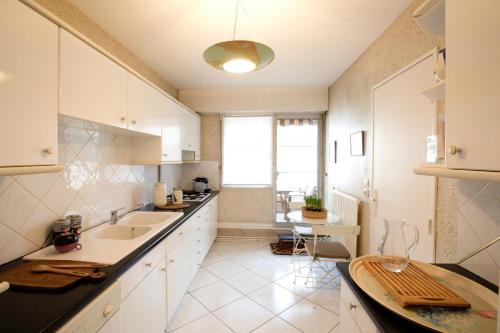 a white kitchen with a sink and a table at Appartement 2 chambres Chartrons in Bordeaux