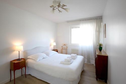 a white bedroom with a white bed and a window at Appartement 2 chambres Chartrons in Bordeaux