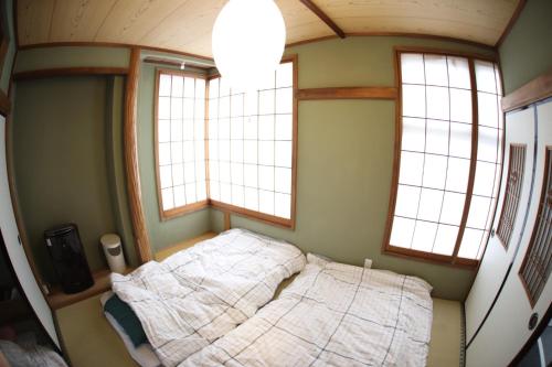 uma pequena cama num quarto com duas janelas em Saitama Kyodo Building - Vacation STAY 02388v em Saitama