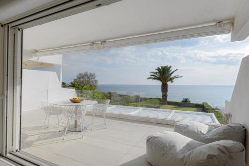 a patio with a table and chairs and a view of the ocean at Luxurious Beachfront Villa Maira in Aghia Marina