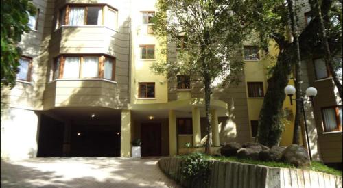 a large yellow building with a driveway in front of it at Apartamento Borges Gramado in Gramado