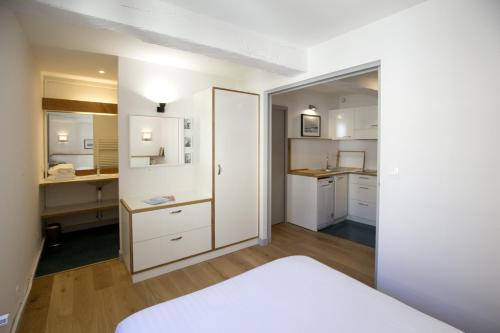 une chambre avec un lit et une cuisine avec des placards blancs dans l'établissement Centre Historique - Tour du Pin 2, à Bordeaux