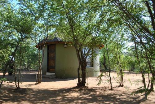 um pequeno edifício no meio de algumas árvores em Rhumbini Lodge em Malamulele