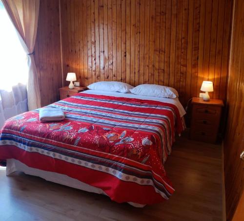 1 dormitorio con 1 cama con manta roja y azul en Turismo Don Hugo, en Puerto Tranquilo