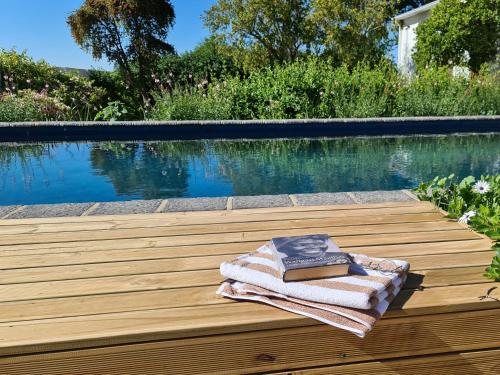 a towel and book sitting on a wooden deck next to a pool at Abbotts Hill in Malmesbury