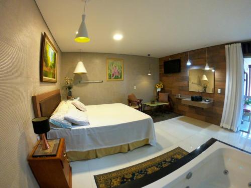 Schlafzimmer mit einem Bett und einer Badewanne in der Unterkunft Pousada Hibisco in Serra do Cipo