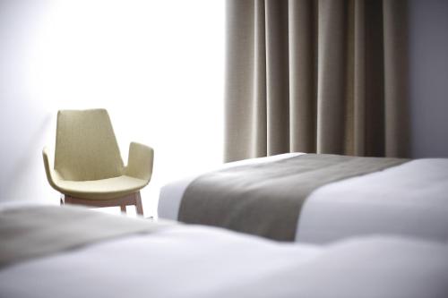 a bedroom with two beds and a chair next to a window at BLEECKER Hotels in Belgrade