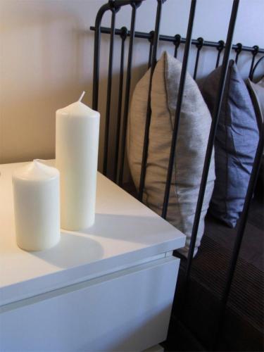 two white candles sitting on a dresser with pillows at City Lodging Apartments in Berlin